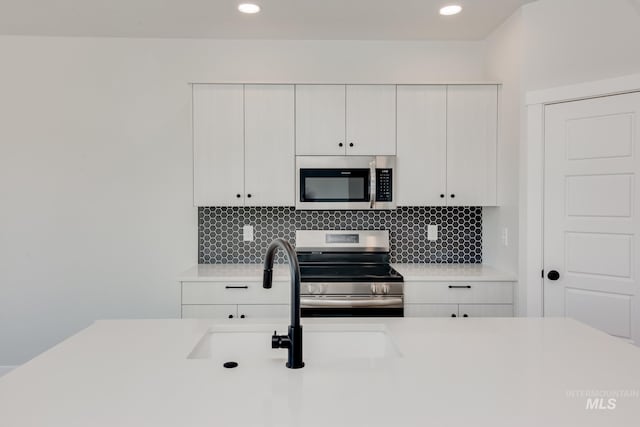 kitchen featuring a sink, appliances with stainless steel finishes, white cabinets, and light countertops