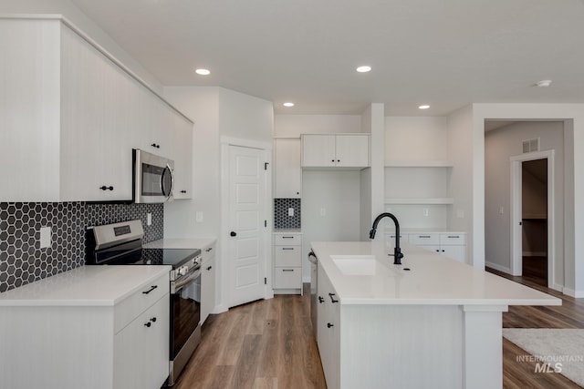 kitchen featuring visible vents, light wood-style flooring, a sink, stainless steel appliances, and light countertops