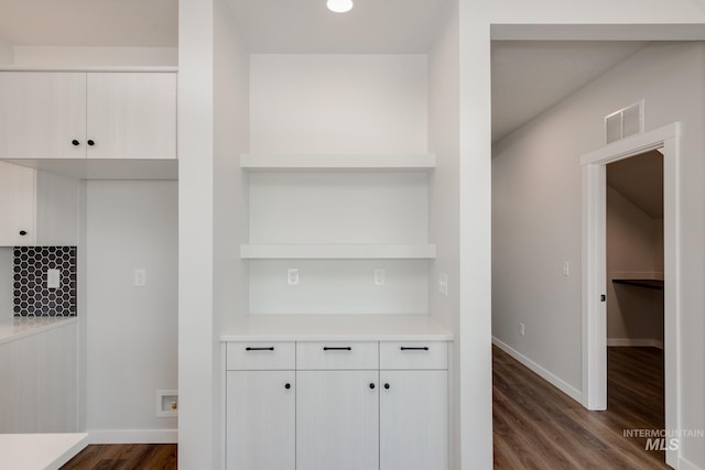 kitchen with white cabinets, dark wood-type flooring, and tasteful backsplash