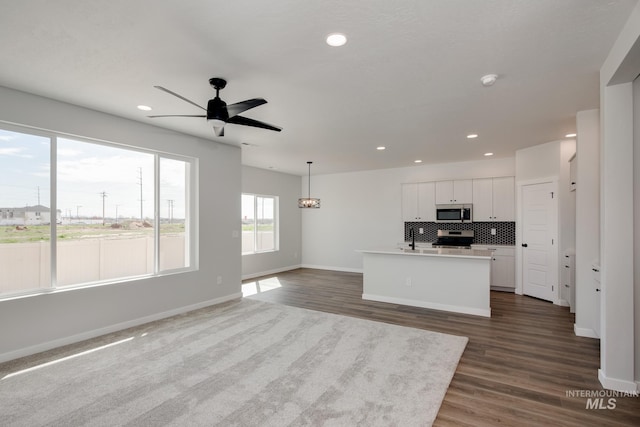 kitchen with a center island with sink, backsplash, recessed lighting, stainless steel appliances, and ceiling fan