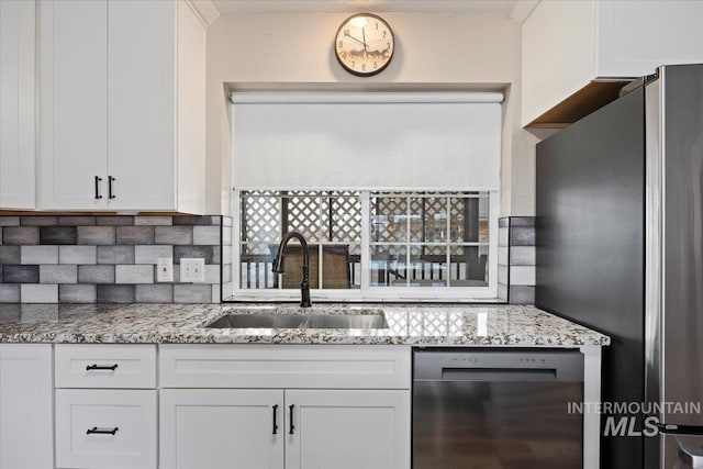 kitchen with light stone countertops, tasteful backsplash, sink, white cabinets, and stainless steel appliances