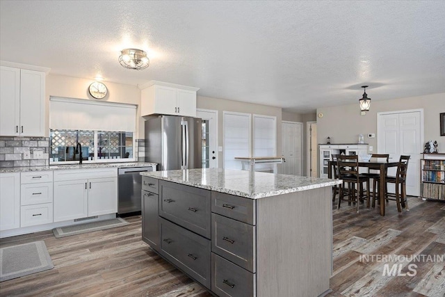 kitchen with white cabinets, appliances with stainless steel finishes, a center island, dark hardwood / wood-style flooring, and sink