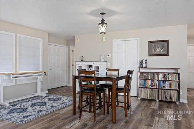 dining area featuring dark wood-type flooring and a textured ceiling