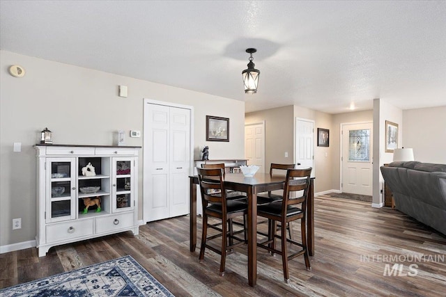 dining space featuring dark wood-type flooring and a textured ceiling