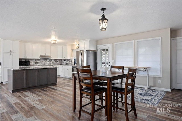 dining space with sink, a textured ceiling, and wood-type flooring