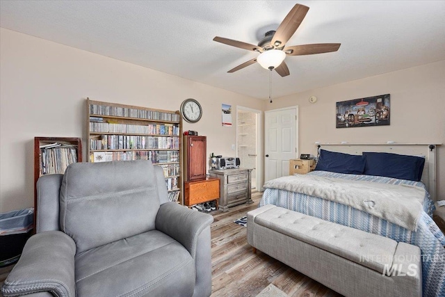 bedroom featuring light wood-type flooring, ceiling fan, and a textured ceiling