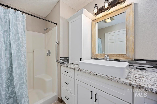 bathroom with backsplash, walk in shower, and vanity