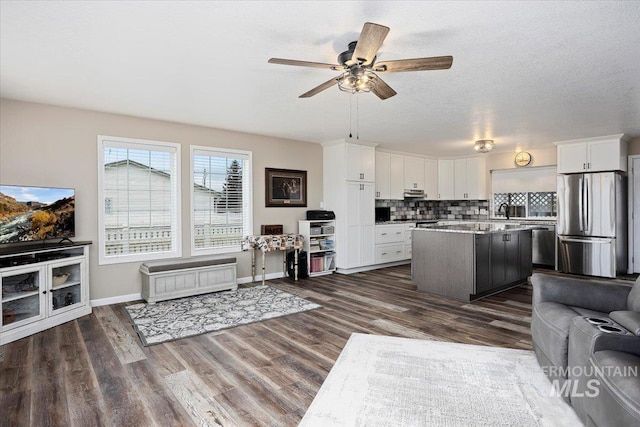 living room with a textured ceiling, dark hardwood / wood-style floors, and ceiling fan