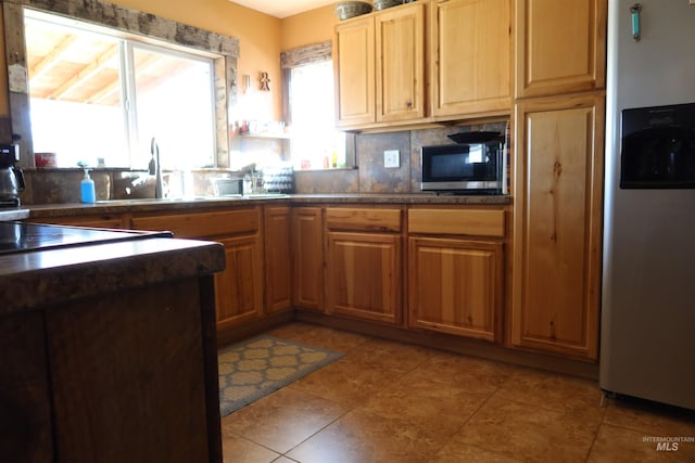 kitchen with backsplash, light tile patterned floors, sink, and appliances with stainless steel finishes