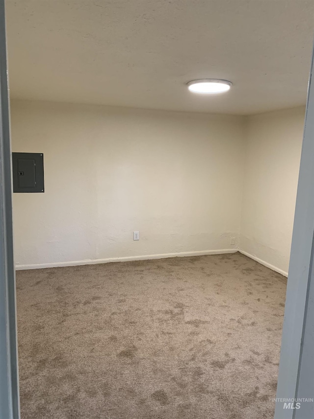 spare room with carpet floors, electric panel, and baseboards