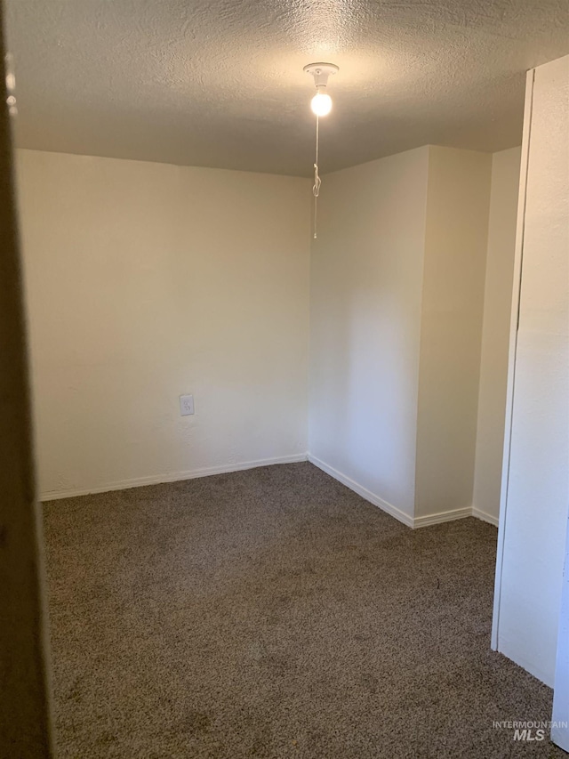 spare room with a textured ceiling, carpet floors, and baseboards