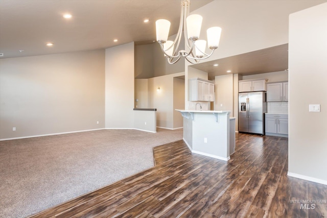 kitchen with tasteful backsplash, a breakfast bar, pendant lighting, a chandelier, and stainless steel fridge with ice dispenser