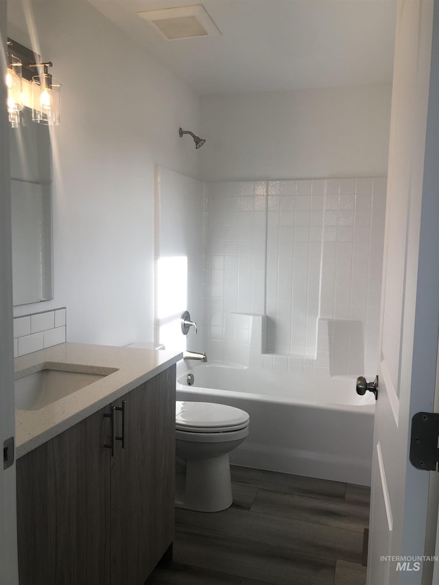 full bathroom featuring washtub / shower combination, hardwood / wood-style flooring, vanity, and toilet