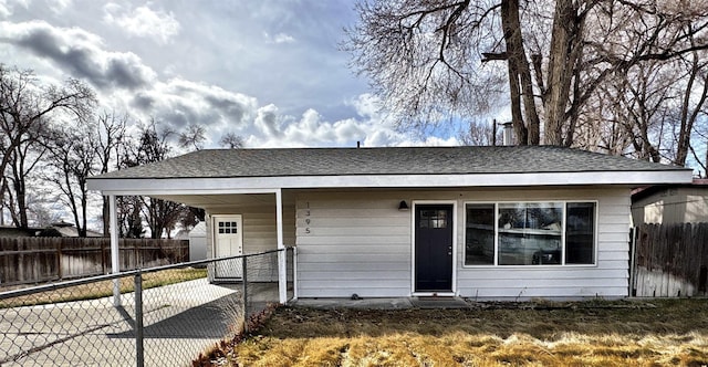 view of front of house featuring an attached carport, driveway, roof with shingles, and fence