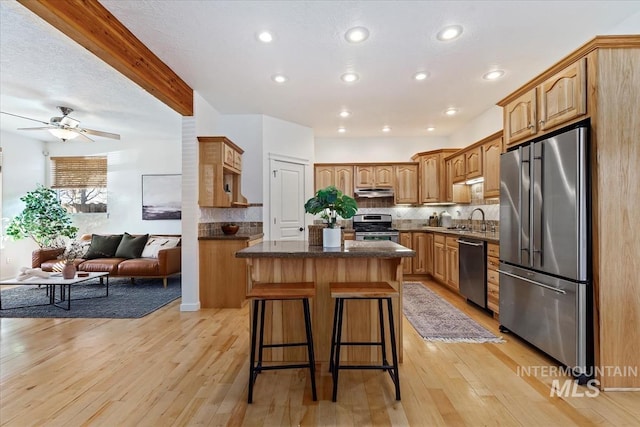 kitchen featuring a center island, light wood finished floors, a breakfast bar area, appliances with stainless steel finishes, and open floor plan