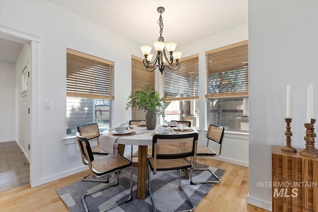 dining area featuring baseboards, light wood-type flooring, and a notable chandelier