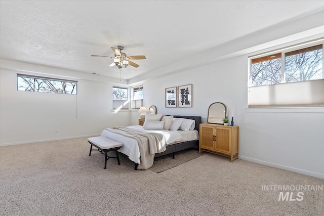 bedroom featuring light carpet, a textured ceiling, a ceiling fan, and baseboards