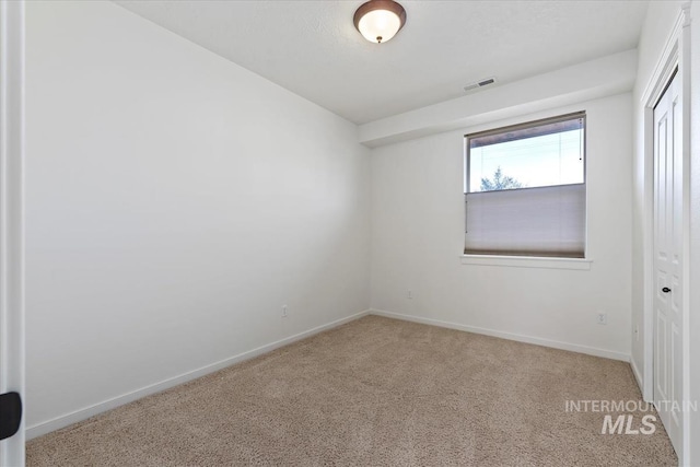 carpeted spare room featuring visible vents and baseboards