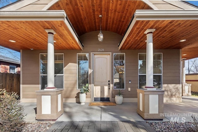 property entrance with covered porch and fence