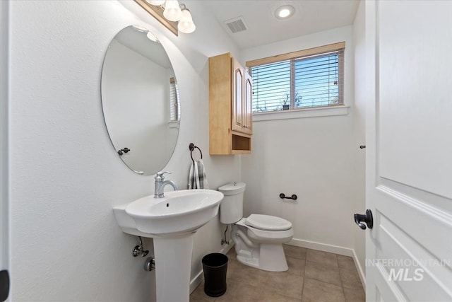 half bathroom featuring tile patterned flooring, visible vents, toilet, and baseboards