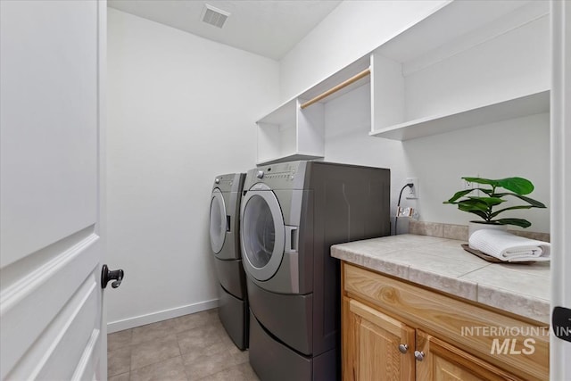 laundry area with cabinet space, washing machine and clothes dryer, visible vents, and baseboards