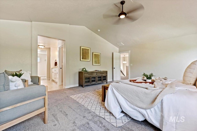 bedroom featuring ensuite bathroom, ceiling fan, light carpet, and vaulted ceiling