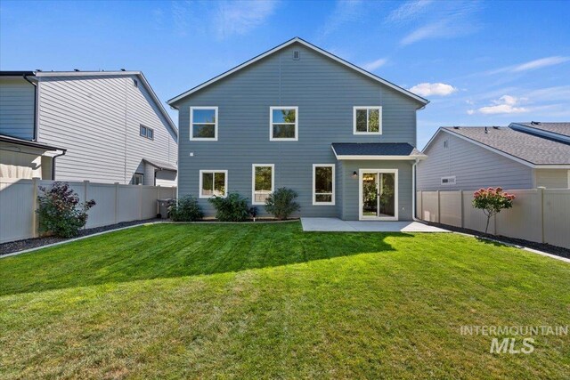 rear view of house featuring a lawn and a patio