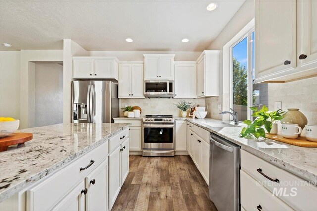 kitchen with tasteful backsplash, white cabinetry, sink, and stainless steel appliances