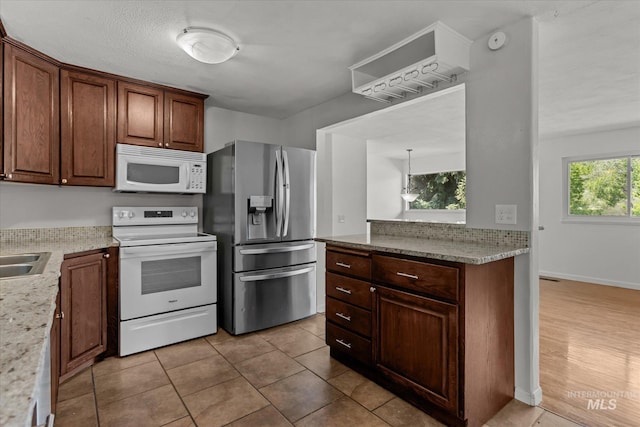 7313 W Court Ave, Boise, ID 83704 - kitchen featuring white appliances, light stone countertops, a sink, and light tile patterned floors