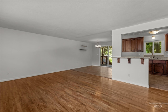7313 W Court Ave, Boise, ID 83704 - unfurnished living room featuring a chandelier, wood finished floors, a sink, and baseboards