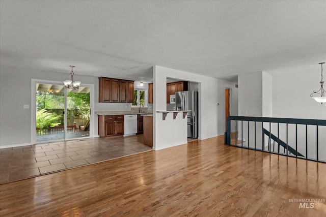 7313 W Court Ave, Boise, ID 83704 - unfurnished living room with a chandelier, wood finished floors, baseboards, and a sink