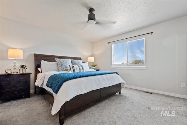 carpeted bedroom with a textured ceiling, a ceiling fan, and baseboards