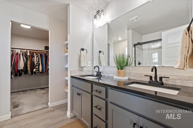 full bath with a stall shower, a sink, wood finished floors, and visible vents