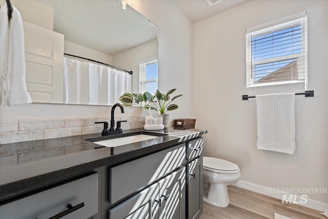 bathroom with wood finished floors, toilet, vanity, and baseboards