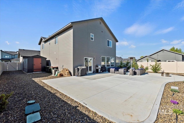 rear view of property featuring a patio, a gate, an outbuilding, a storage shed, and a fenced backyard