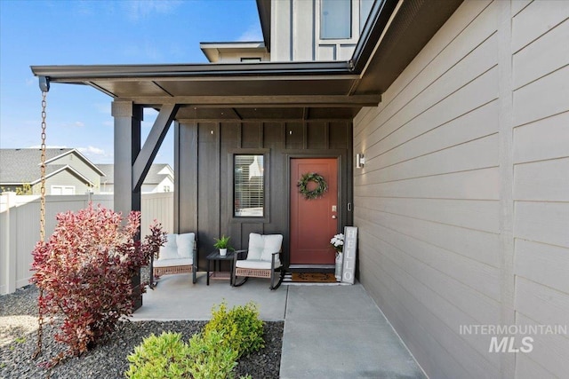 doorway to property featuring fence and board and batten siding