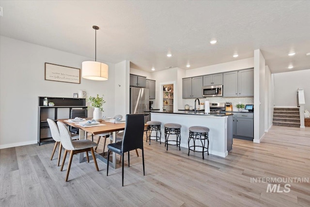dining room featuring stairway, light wood-style floors, recessed lighting, and baseboards