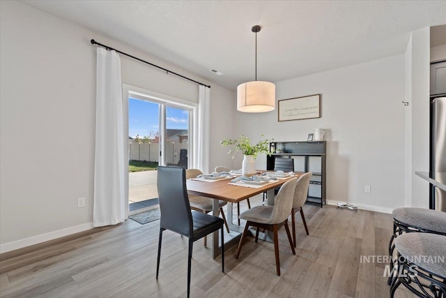 dining area featuring visible vents, light wood finished floors, and baseboards