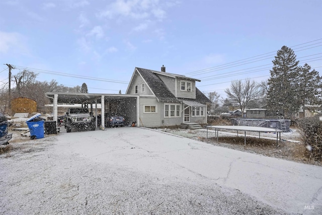 rear view of property featuring a carport and a trampoline