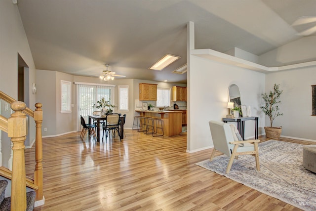 interior space featuring stairway, baseboards, ceiling fan, vaulted ceiling, and light wood-style floors