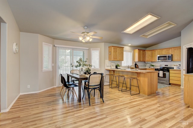 dining room with ceiling fan, baseboards, lofted ceiling, and light wood-style floors