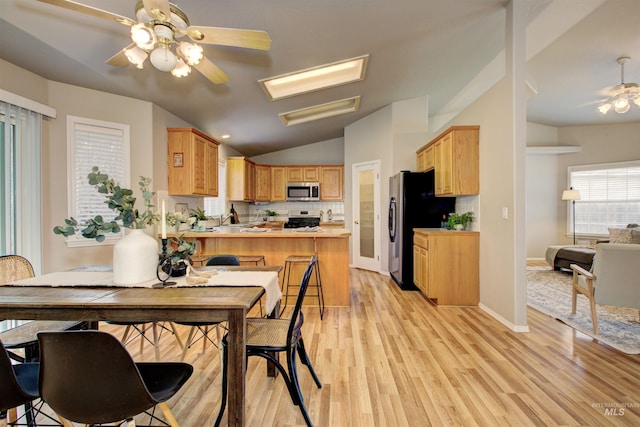 dining room featuring lofted ceiling, light wood-style flooring, baseboards, and ceiling fan