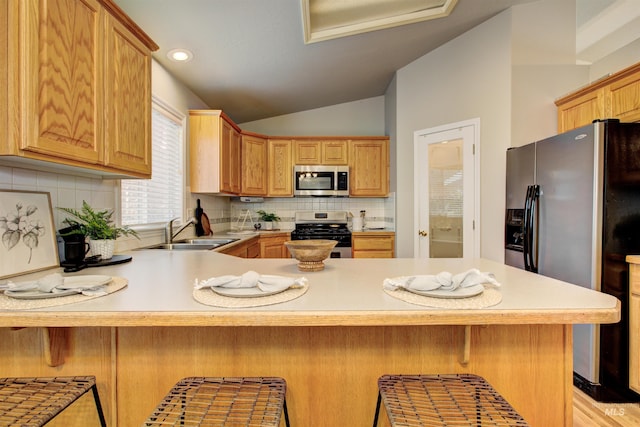 kitchen with a sink, stainless steel appliances, lofted ceiling, and light countertops