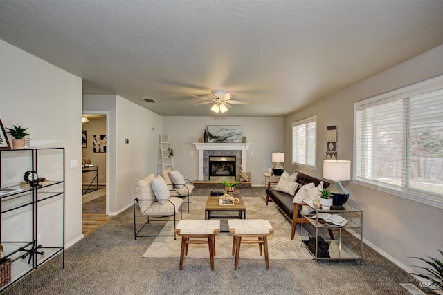 carpeted living room with a fireplace, a ceiling fan, visible vents, and baseboards