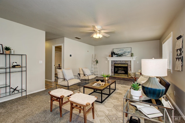 living room featuring a tile fireplace, a ceiling fan, visible vents, and baseboards