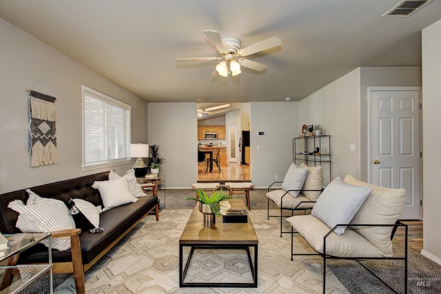 living room featuring visible vents, baseboards, and ceiling fan