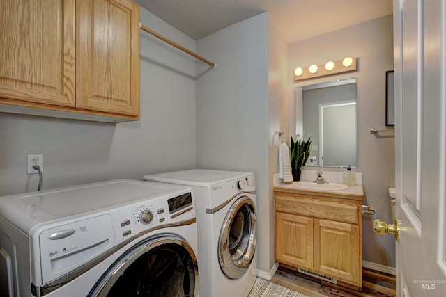 laundry room featuring baseboards, laundry area, wood finished floors, washer and dryer, and a sink