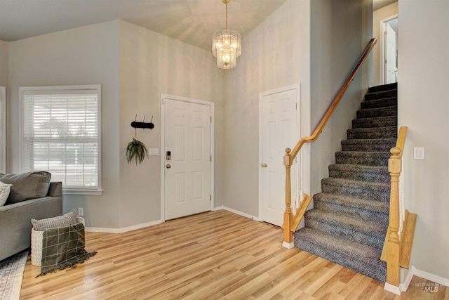 entrance foyer with stairway, a notable chandelier, light wood-style flooring, and baseboards