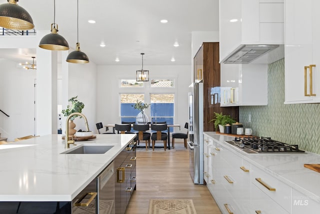 kitchen featuring sink, white cabinets, premium range hood, and appliances with stainless steel finishes