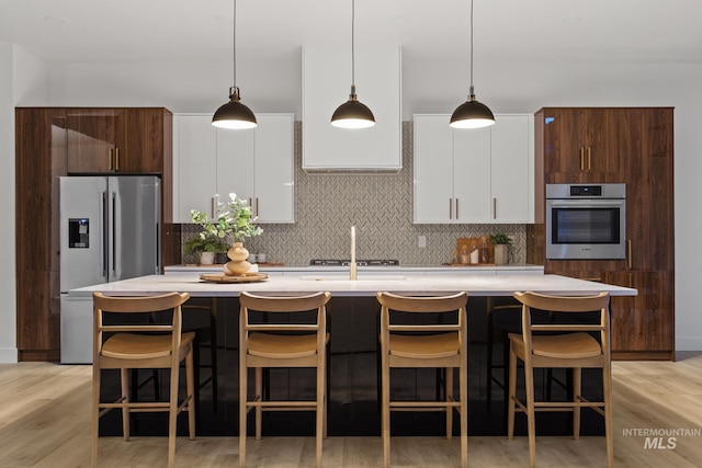 kitchen featuring stainless steel appliances, a kitchen island with sink, and pendant lighting